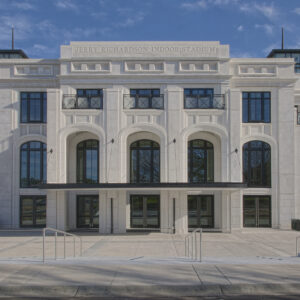 Front view of Jerry Richardson Indoor Stadium, featuring large arched windows and a symmetrical facade against a blue sky.