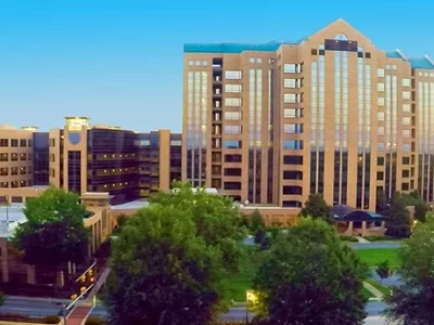 Aerial view of a large office building complex surrounded by trees, with a clear blue sky in the background.