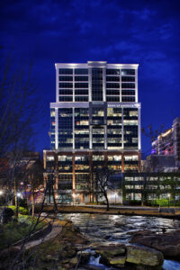 A tall building with "Bank of America" signage is lit up against a night sky, with trees in the foreground.