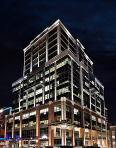 A modern high-rise building with illuminated windows and Bank of America signage at night.