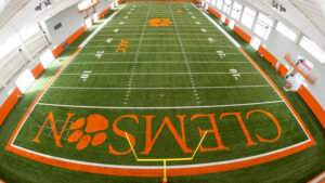 Indoor football field with "Clemson" logo and orange and white markings.