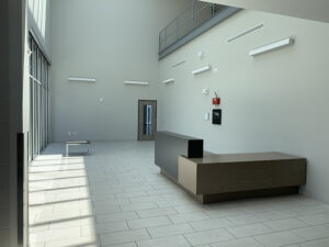 A modern, empty lobby with a reception desk, high ceiling, large windows, white walls, and tile flooring.