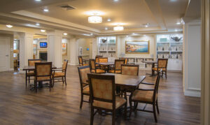 A well-lit, empty dining room with wooden tables and chairs, artwork on the walls, and recessed lighting on the ceiling.