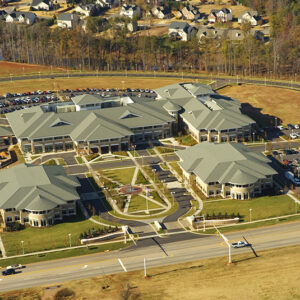 Aerial view of a large educational facility with multiple connected buildings and a surrounding parking area.