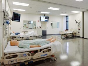 Hospital training room with medical mannequins in beds, monitoring equipment, and sterile environment.