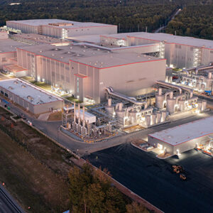 Aerial view of a large industrial complex with multiple buildings and roads, illuminated at night.