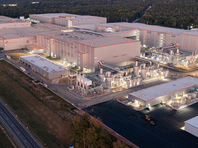 Aerial view of a large industrial complex with multiple buildings and roads, illuminated at night.