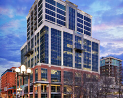 Design-Build Projects Tall glass and brick office building with "Bank of America" sign, set against a vibrant evening sky, viewed from a nearby street.